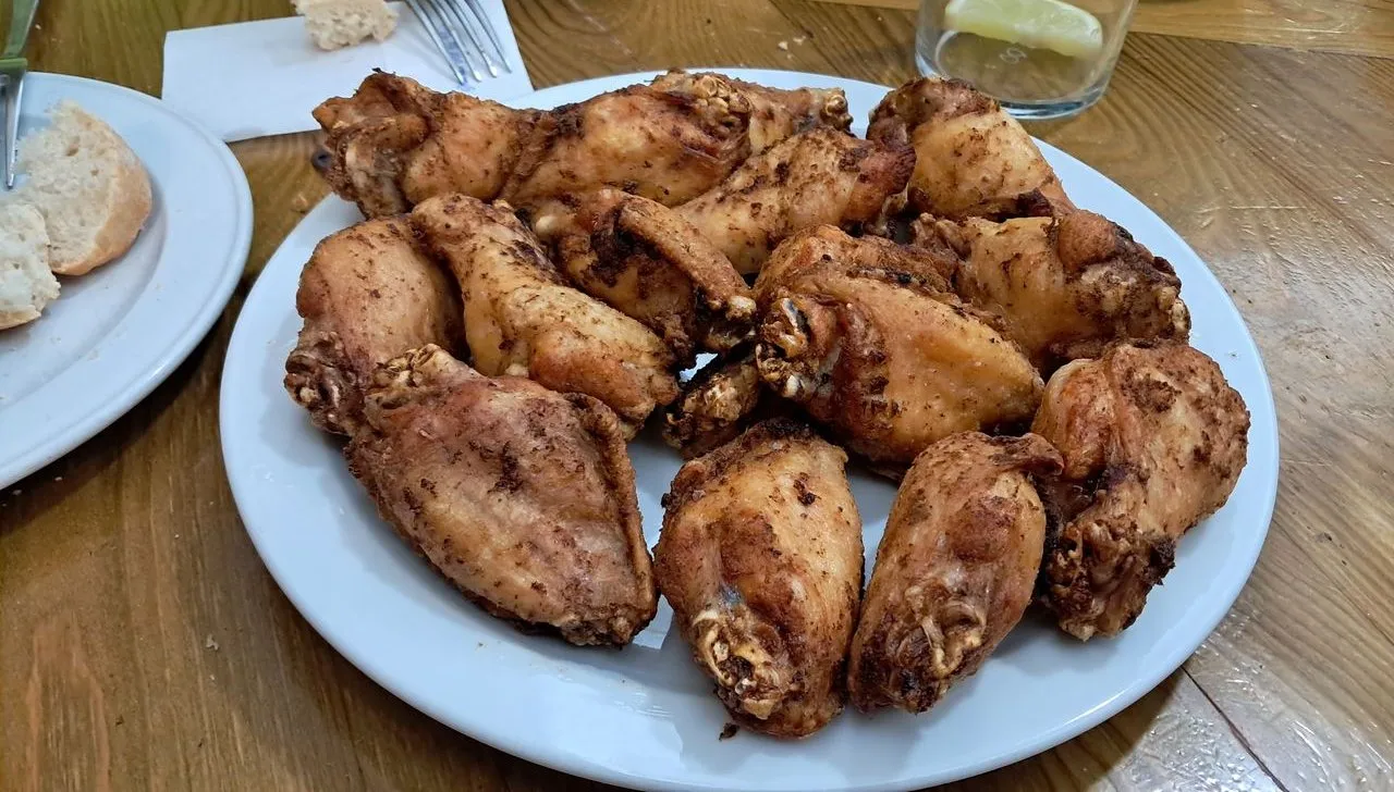 Plato de alitas de pollo fritas sobre una mesa de madera